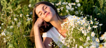 девушка лежит на траве среди ромашек