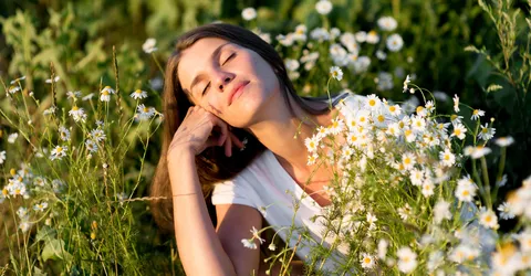 девушка лежит на траве среди ромашек