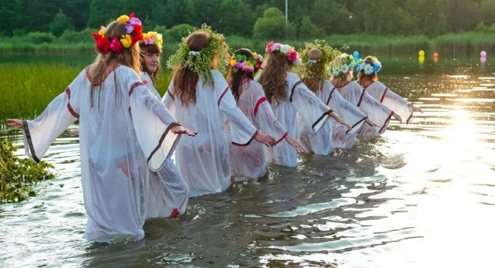 девушки стоят в воде с венками на голове