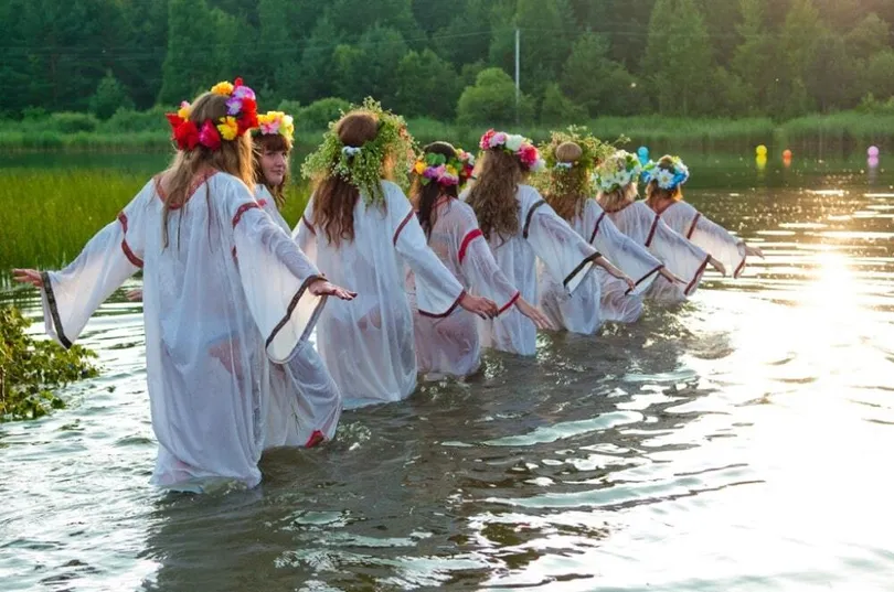 девушки стоят в воде с венками на голове