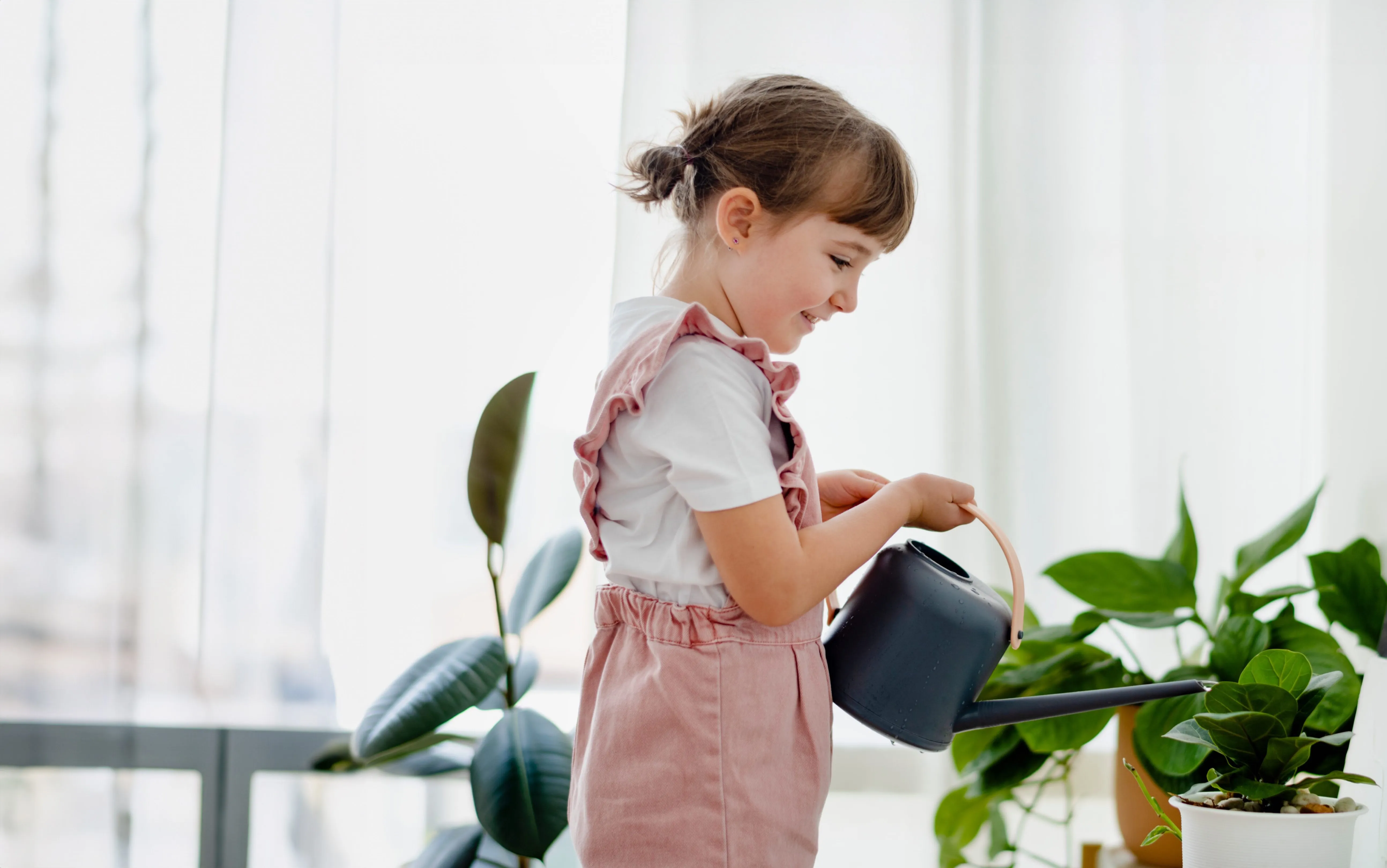девочка поливает растения