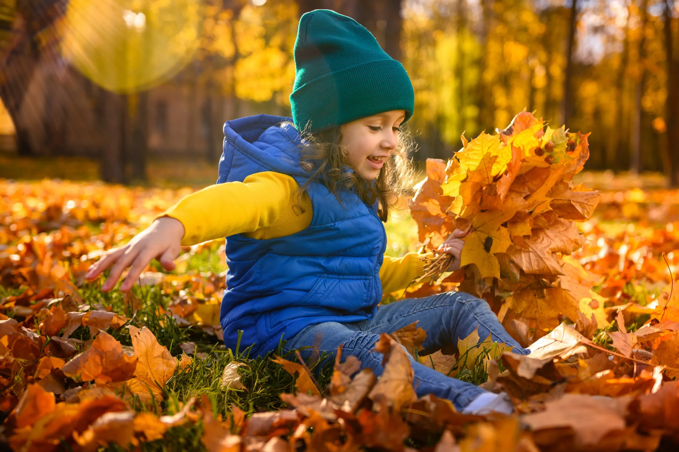 девочка играет с осенней листвой