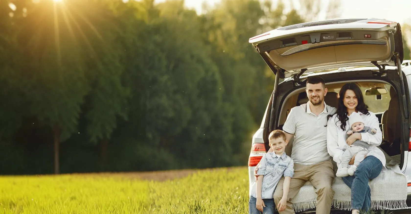 семья сидит на багажнике машины